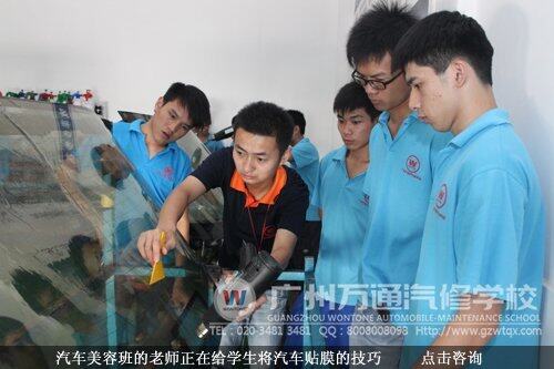 汽车美容班的老师正在给学生将汽车贴膜的技巧